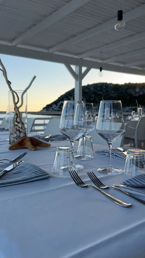 Calici e tovaglie a righe sulla terrazza affacciata sul mare