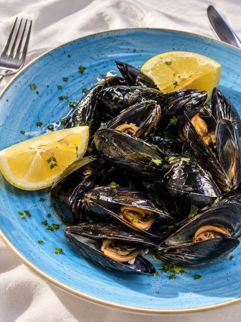 Cozze in un piatto di ceramica blu con limone